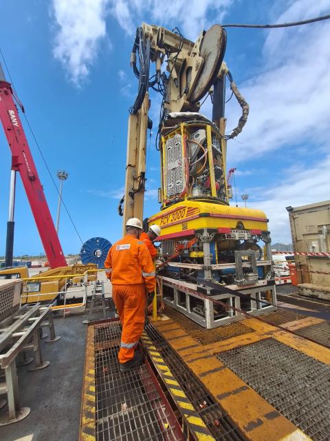 Técnico da DT Marine acompanha um equipamento amarelo identificado como FCV 3000, suspenso no convés, com guindaste ao fundo